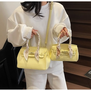 Detail of yellow lychee leather handbags with scarf handles on wooden stairs