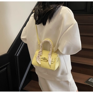Detail of yellow pebbled leather handbag with silk scarf handle and metal clasp