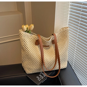 Détail d'un grand sac fourre-tout en paille tissée avec anses en cuir sur fond noir