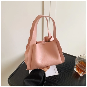 Detail shot of a pink bucket bag with wavy edges and litchi texture leather material