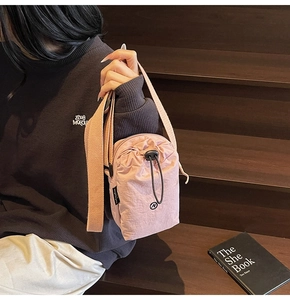 Detailed macro view of pink nylon fabric texture and logo on the sporty crossbody bag