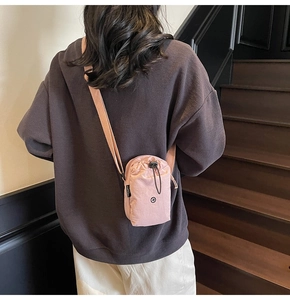 Detail of soft pink nylon crossbody bag with drawstring closure and slim shoulder strap
