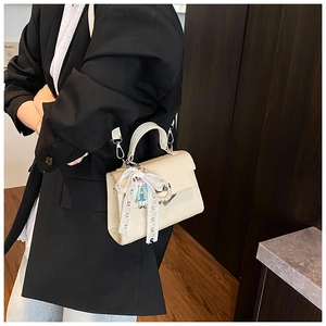 Détail du sac à main crème texturé litchi avec nœud en dentelle et breloque mignonne