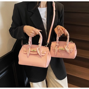 Close-up of pink lychee leather handbags with gold twist locks and silk scarf handle detail