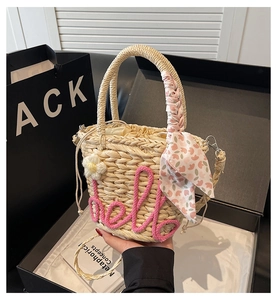 Detail of cream straw bucket bag with pink hello embroidery and floral scarf handle
