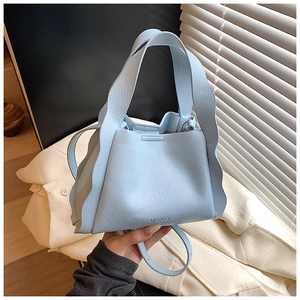 Detail of light blue leather bucket bag with wavy edge design and MUDUO brand logo