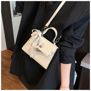Détail de sac trapèze en cuir crème avec nœud en dentelle et accessoires de perles chic