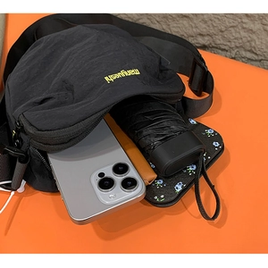 Detail view of black nylon crossbody bag interior showing phone umbrella and wallet storage
