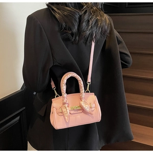 Pink lychee grain leather handbag with gold clasp and decorative silk scarf on handle