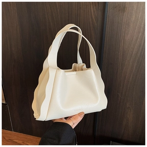 Detailed shot of cream bucket bag with wavy pleated handle and embossed logo