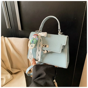 Détail du sac bleu clair en cuir grainé avec ruban en dentelle et pendentif