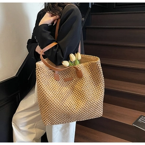 Détail d'un sac cabas en paille tressée avec anses en cuir marron et doublure