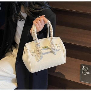 Detail of white lychee leather handbag with gold twist lock and floral handle scarf