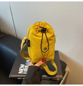 Detail of yellow nylon crossbody bag with drawstring pocket and wide shoulder strap