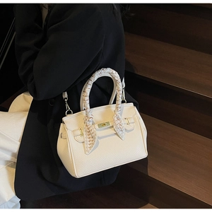 Detail view of cream handbag with luxury silk-wrapped handle and golden clasp