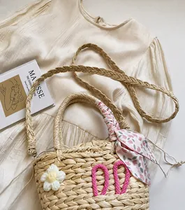 Detailed view of handmade straw woven bag with floral ribbon and braided strap
