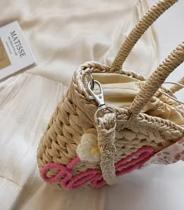 Detail of straw woven bag with white satin drawstring liner and pink embroidery detail