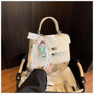 Gros plan sac à main blanc motif litchi avec nœud en dentelle et pendentif poupée mignon