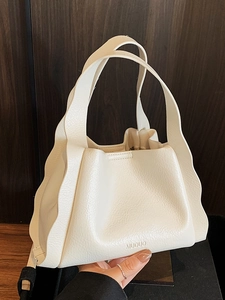 Minimalist beige bucket bag in lychee leather featuring stylish wavy pleated edges