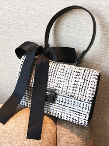Elegant black and white tweed crossbody bag with a large ribbon bow and metal lock clasp