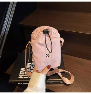 Close-up of pink nylon crossbody bag with drawstring closure on wooden stairs