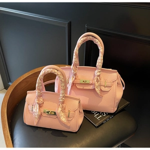 Close-up of two pink lychee pattern leather handbags with silk scarves on a wooden chair