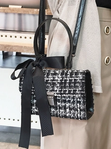 Elegant black and white tweed crossbody bag with a satin bow and silver metal buckle