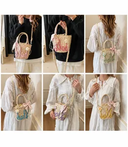 Detail view of woven straw bucket bag with colorful hello design and floral scarf handle