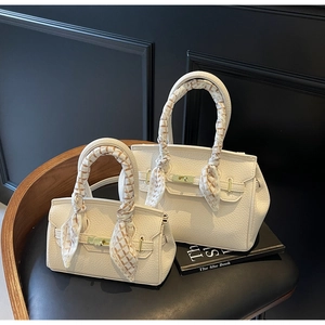 Close-up of white lychee leather handbags with elegant silk scarves wrapped around handles