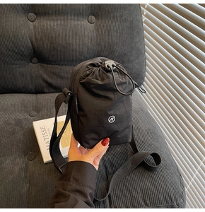 Detail view of black nylon drawstring crossbody bag with N logo and adjustable strap