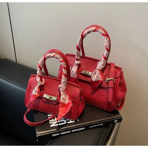 Detail of red lychee grain leather handbags with metal turn-lock and silk scarf handle