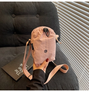 Close-up of pink nylon crossbody bag with drawstring closure and adjustable strap