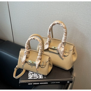 Close-up of beige lychee grain leather handbags with silk scarves on handles