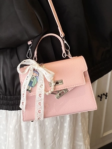 Sac à main style Kelly rose avec breloque perle et nœud en dentelle porté par un modèle