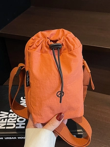 Orange nylon mini crossbody bag with drawstring closure and wide shoulder strap