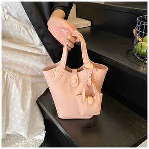 Close-up of pink litchi grain leather bucket bag with a matching mini charm