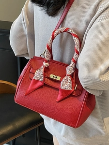 Elegant red lychee leather handbag with gold lock and silk scarf wrapped handle
