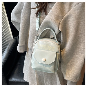 Gros plan d'un sac bandoulière vert menthe avec imprimé STORY porté par un mannequin