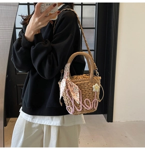 Detail of handmade straw bucket bag with floral scarf handle and 3D flower accent