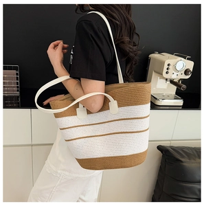 Détail du sac de plage tissé à rayures avec fines bretelles blanches et texture en paille