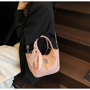 Detail of pink croc-embossed bucket bag with decorative silk scarf and silver metal buckle