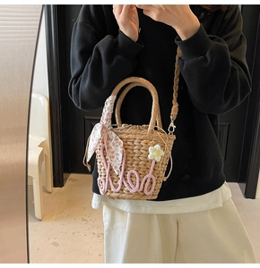 Detail view of woven straw bag with floral scarf, 3D knit flower and drawstring lining