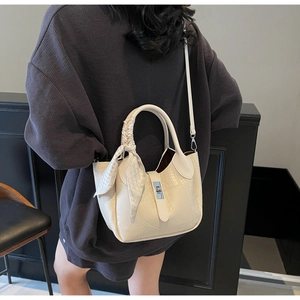 Detail view of cream crocodile texture bucket bag with silk scarf on the handle