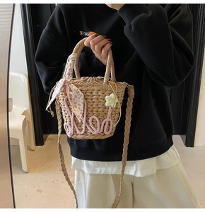Detail view of woven straw bucket bag with pink rope embroidery and floral scarf handle