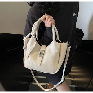 Detail view of cream bucket bag with faux crocodile texture and printed silk scarf handle