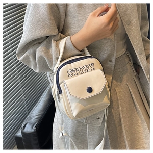Détail du mini sac blanc avec imprimé STORY et bordure bleue porté par le mannequin