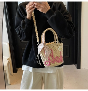 Detail of straw bucket bag with pink rope lettering and floral scarf handle