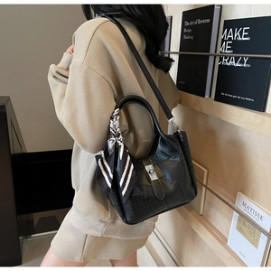 Detail of black crocodile texture bucket bag with silver buckle and striped silk scarf
