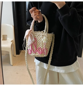 Detail of straw handbag with pink Aloha embroidery, floral scarf and knit flower