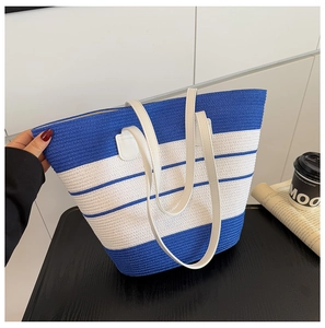 Détail de la texture du sac en paille tressé à rayures bleues et blanches avec anse blanche
